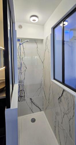 La salle de bains est pourvue d'une douche en marbre et d'une fenêtre. dans l'établissement Daulis Villa Port Nature 1, au Cap d'Agde