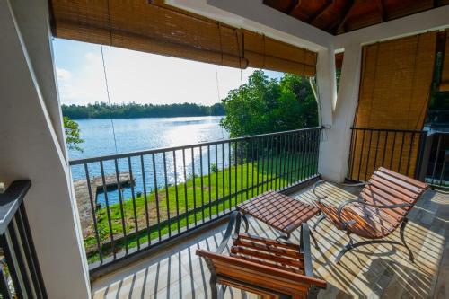 a balcony with two chairs and a view of the water at Ayuwaters Authentic Yoga and Ayurveda Retreat by the Bentota River All Inclusive in Bentota