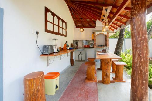 a kitchen with wooden tables and benches in a room at Paradise Sunrise Villa in Ahungalla