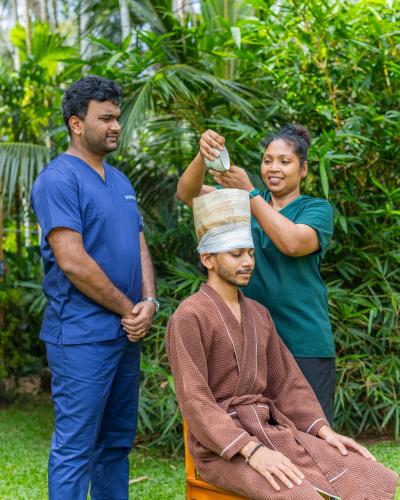 a man getting his head wrapped in a bandana at Ayuwaters Authentic Yoga and Ayurveda Retreat by the Bentota River All Inclusive in Bentota