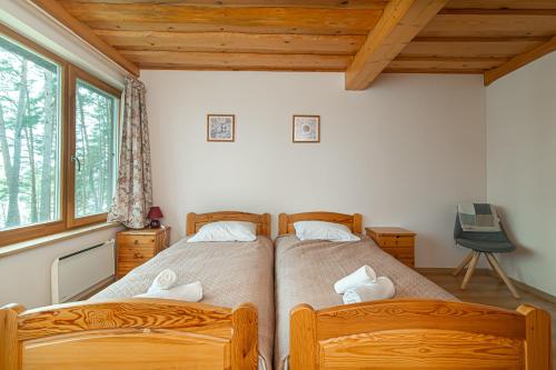 two twin beds in a bedroom with wooden ceilings at Villa Green in Molėtai