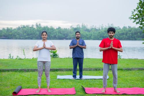 three people doing yoga in front of a body of water at Ayuwaters Authentic Yoga and Ayurveda Retreat by the Bentota River All Inclusive in Bentota