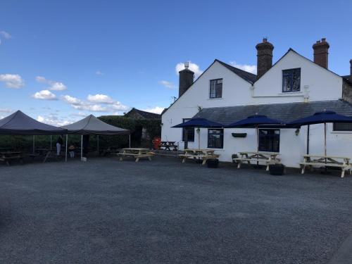 un edificio blanco con mesas de picnic y sombrillas en Blue Lion Inn, en Lewdown