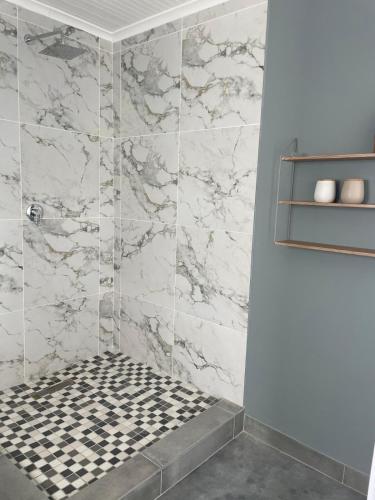 a bathroom with a shower with a black and white tiles at Calypso beach holiday in Langebaan