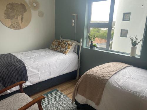 a bedroom with two beds and a window at Calypso beach holiday in Langebaan