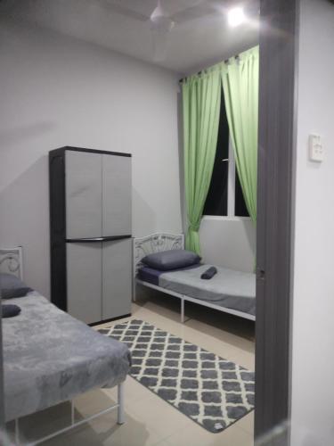 a room with two beds and a window with green curtains at Kenangan Homestay Kemaman in Kampong Chendar