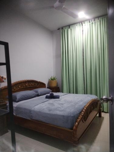 a bedroom with a bed with a green curtain at Kenangan Homestay Kemaman in Kampong Chendar