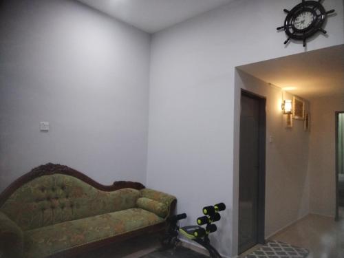 a living room with a couch and a clock on the wall at Kenangan Homestay Kemaman in Kampong Chendar