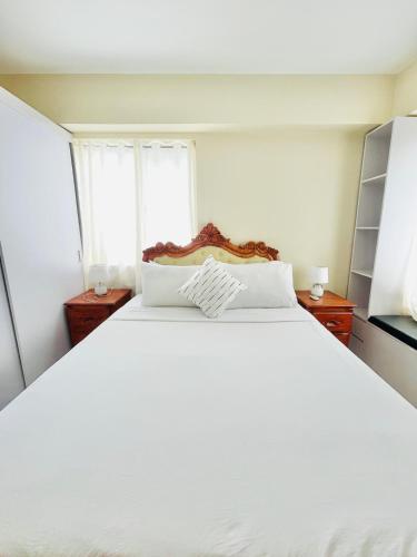 イロイロにあるC3 Elegant 2BR Condo with Pool Viewの窓のある部屋にある白いベッド