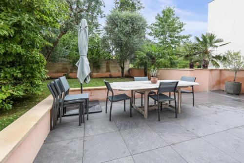a patio with a table and chairs and an umbrella at Maison Jacoulet - Welkeys in Saint-Cloud