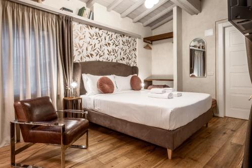 a bedroom with a large bed and a chair at La Bartolomea Home & Suite in Pitigliano