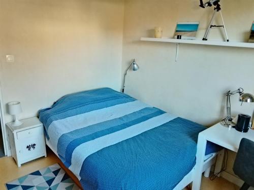 a small bedroom with a blue bed and a desk at Chambre au calme près du centre historique de Vannes in Vannes