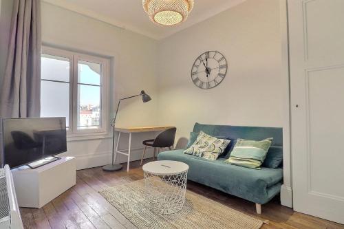 un salon avec un canapé et une horloge au mur dans l'établissement Modern and Cozy Studio in the Heart of Perrache Lyon, à Lyon