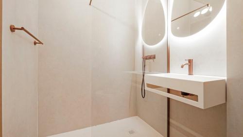 une salle de bain blanche avec un lavabo et une douche dans l'établissement Luxueux appartement avec terrase sur la mer, à Grimaud