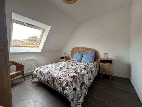 - une chambre avec un lit doté d'un couvre-lit floral et d'une fenêtre dans l'établissement La Brise Marine, à Barneville-Carteret