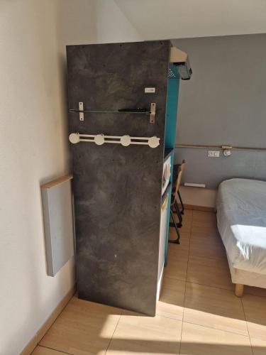 a metal door in a room next to a bed at Hôtel Acajou in Argelès-sur-Mer