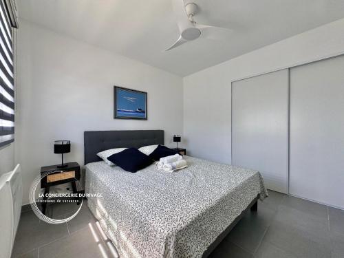 une chambre avec un lit et un ventilateur de plafond dans l'établissement Le Frangipanier - Port de Carqueiranne et plages, à Carqueiranne
