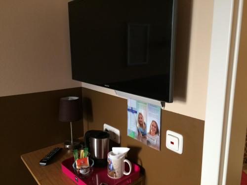 a flat screen tv hanging on a wall with a table at Hotel Sandmanns am Dom in Cologne