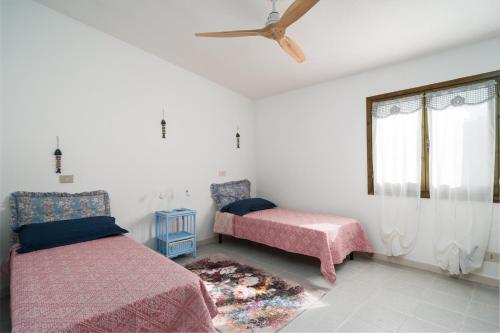 a bedroom with two beds and a ceiling fan at Azzurra in Orosei