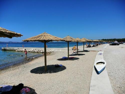 a beach with umbrellas and a boat on it at Apartmani Danica in Pirovac