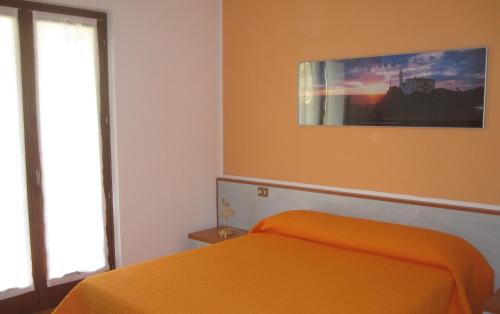 ブレンゾーネにあるAppartamenti Chemasiのベッドルーム1室(オレンジ色のベッド1台付)が備わります。壁には絵画が飾られています。