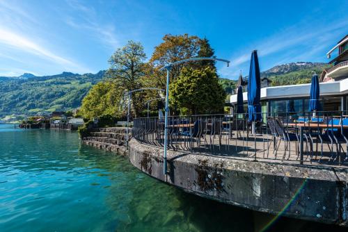 a restaurant with tables and chairs next to the water at Superior Hotel Nidwaldnerhof in Beckenried