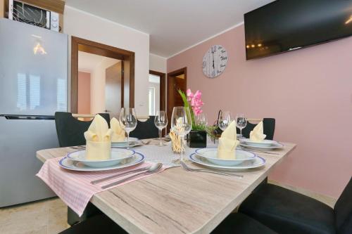 a dining room table with plates and wine glasses at Apartment ErMa in Zaton