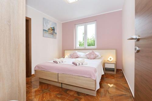 a bedroom with a bed with pink pillows and a window at Apartment ErMa in Zaton