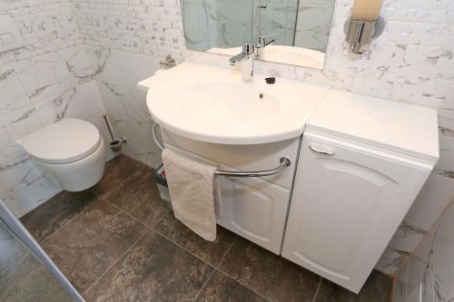 a white bathroom with a sink and a toilet at Apartment ErMa in Zaton