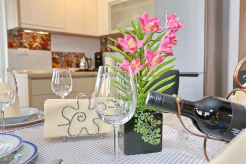 a table with wine glasses and a vase of pink flowers at Apartment ErMa in Zaton