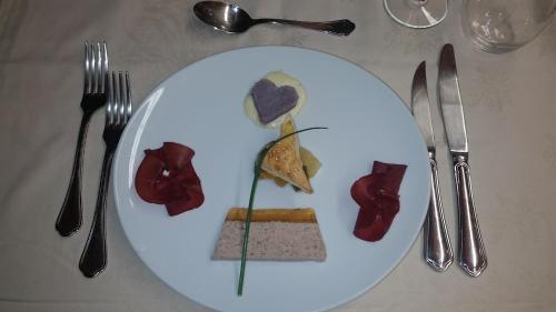 a white plate of food on a table with silverware at Osteria Anzonico in Anzonico