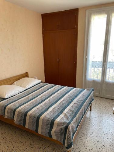 une chambre avec un lit avec une couverture rayée dans l'établissement Appartement près de la mer, à Argelès-sur-Mer