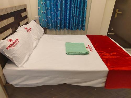 a bed with white sheets and a green towel on it at Hotel SONIA MAHI INN KANYAKUMARI in Kanyakumari