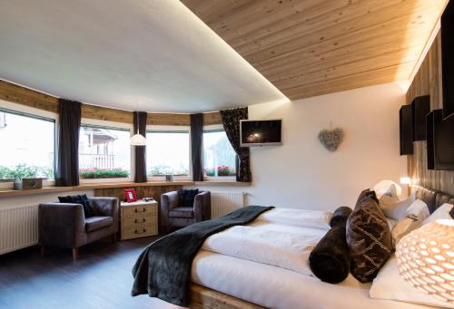a bedroom with a large bed and two chairs at Hotel Chalet S - Dolomites Design - adults recommended in Selva di Val Gardena