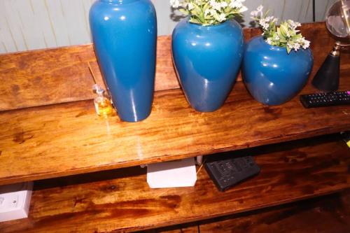 three blue vases sitting on top of a wooden table at Jelani Space's Luzira Apartment in Kampala