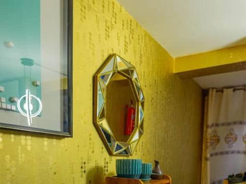 a mirror on a yellow wall in a bathroom at Jelani Space's Luzira Apartment in Kampala