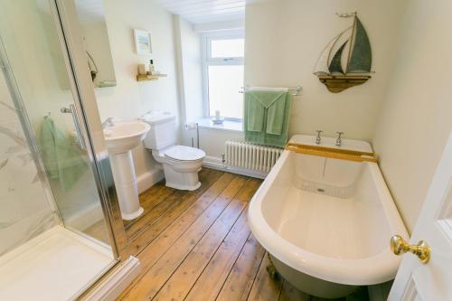 a bathroom with a tub and a sink and a shower at Glan Y Mor in Beaumaris