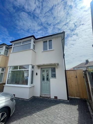 a white house with a car parked in front of it at The Crescent-Modern Coastal Home in Blackpool