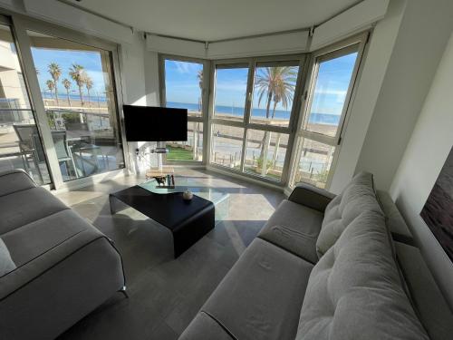 a living room with a couch and a tv at PRIMERA LINEA PLAYA PATACONA, VALENCIA in Valencia