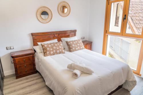 a bedroom with a large white bed with a window at Amplio Apartamento en Llanes Centro in Llanes