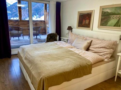 a bedroom with a large bed and a balcony at Ski Chalet Rinerhorn in Glaris