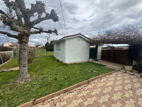 un pequeño cobertizo en un patio con un árbol en La petite condemine, en Beaumont-sur-Grosne