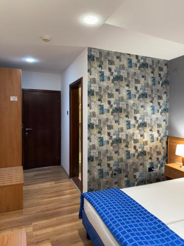 a bedroom with a bed and a tile wall at Motel M Vlasenica in Vlasenica