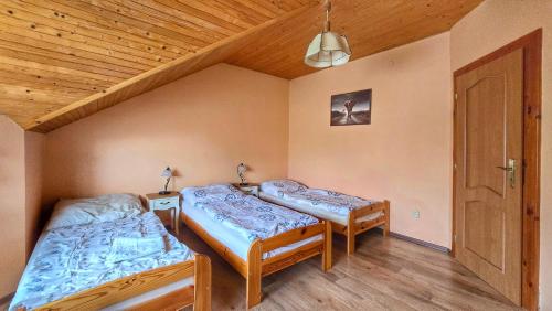two beds in a room with a wooden ceiling at Clara Valis - Village House in Doľany