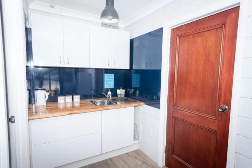 a kitchen with white cabinets and a wooden door at Anchors Away in Bicheno
