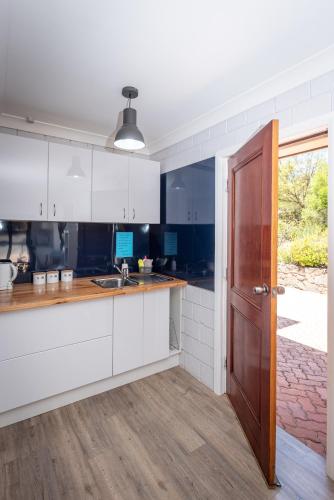 a kitchen with white cabinets and a wooden door at Anchors Away in Bicheno