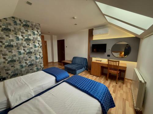 a hotel room with two beds and a desk at Motel M Vlasenica in Vlasenica