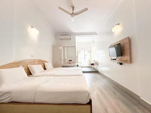 a bedroom with two beds and a flat screen tv at Hotel Vellara in Bengaluru