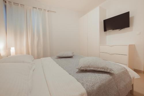 een witte slaapkamer met een bed en een flatscreen-tv bij Center Brela Apartment in Brela