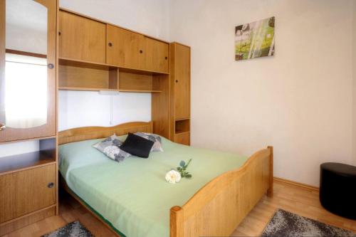 a bedroom with a bed with green sheets and wooden cabinets at Apartments Grozdana in Baška